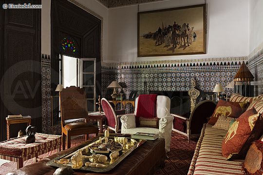 Moroccan living room with original wall tiling and red and ivory striped sofa in 20th century riyad in the medina of Marrakesh with interior restoration by Jean-Louis Raynaud and Kenyon Kramer